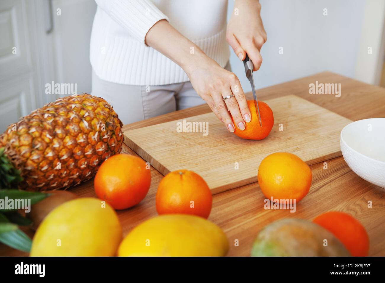 Ragazza mani di taglio frutta sul tagliere, primo piano colpo. Concetto di alimentazione sana. Cibo crudo Foto Stock