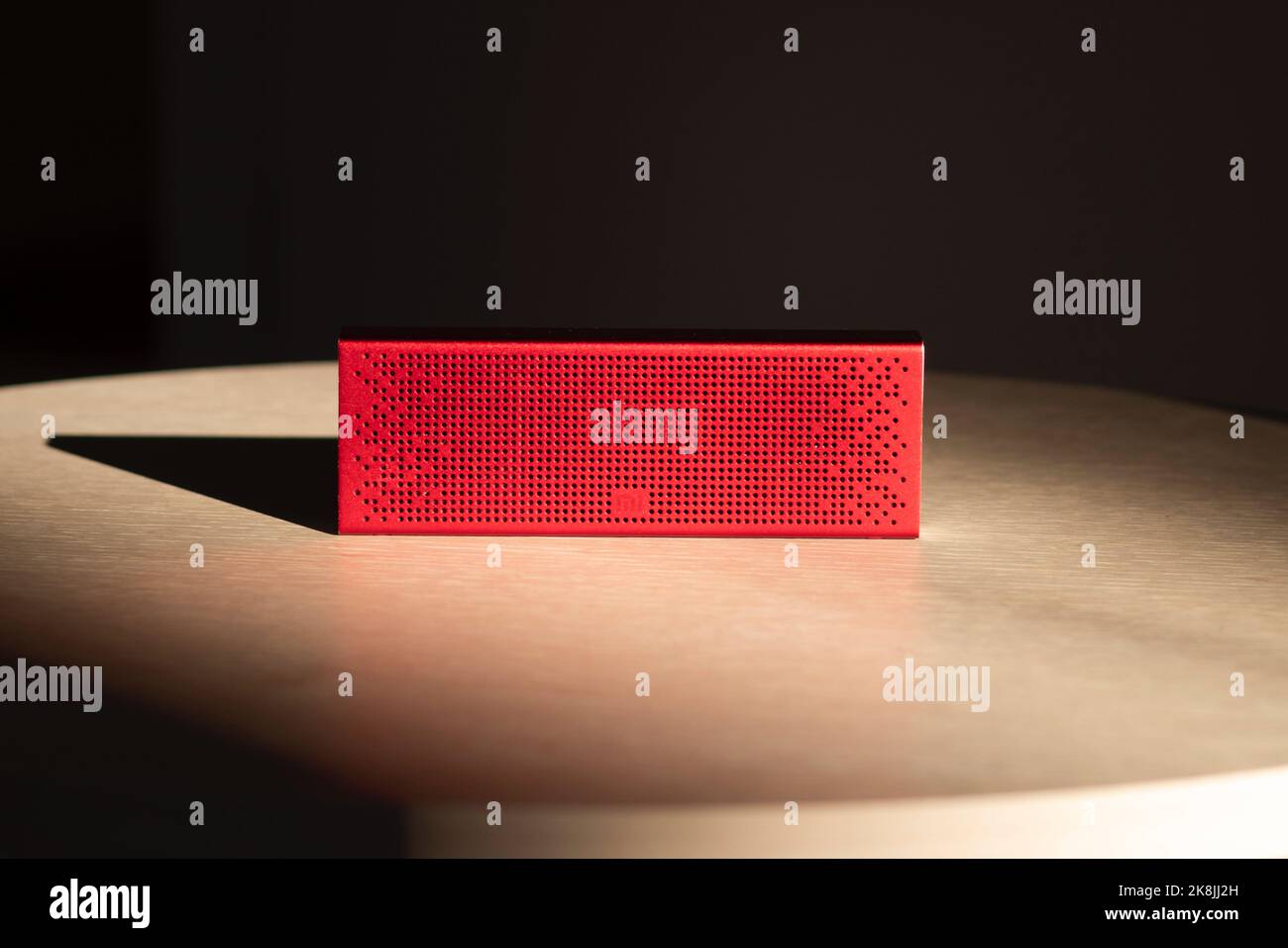 Poznan, Polonia - 10.20.2022: Xiaomi mi Bluetooth Speaker altoparlante portatile di musica rossa situato su un tavolo di legno ai raggi del sole Foto Stock