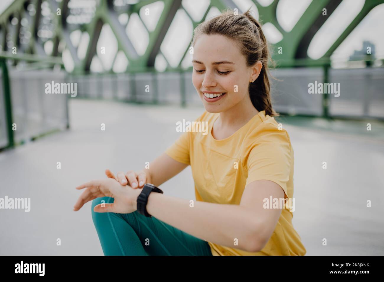 Giovane donna che controlla smartwatch in città, preparandosi per la corsa, stile di vita sano e concetto di sport. Foto Stock