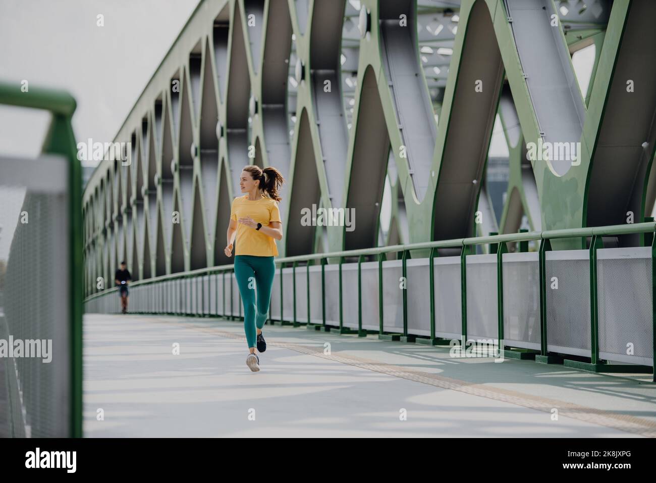 Giovane donna che fa jogging al ponte della città, stile di vita sano e concetto di sport. Foto Stock
