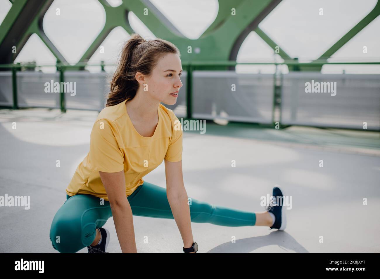 Giovane donna che fa stretching in città, preparandosi per la corsa, stile di vita sano e concetto di sport. Foto Stock