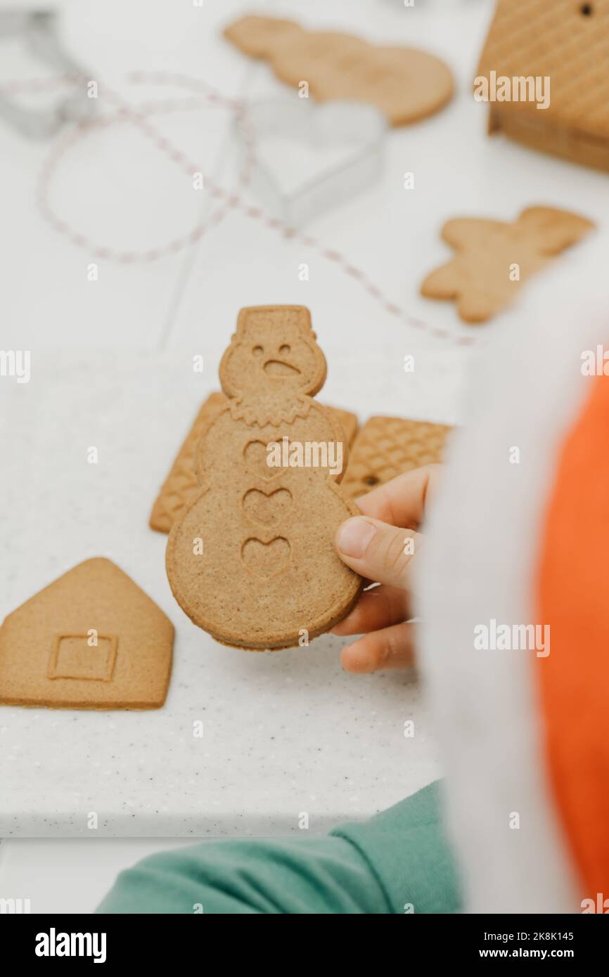 Il bambino sta tenendo un biscotto di pan di zenzero nella forma di un pupazzo di neve. Cucinare i biscotti di Natale. Foto Stock