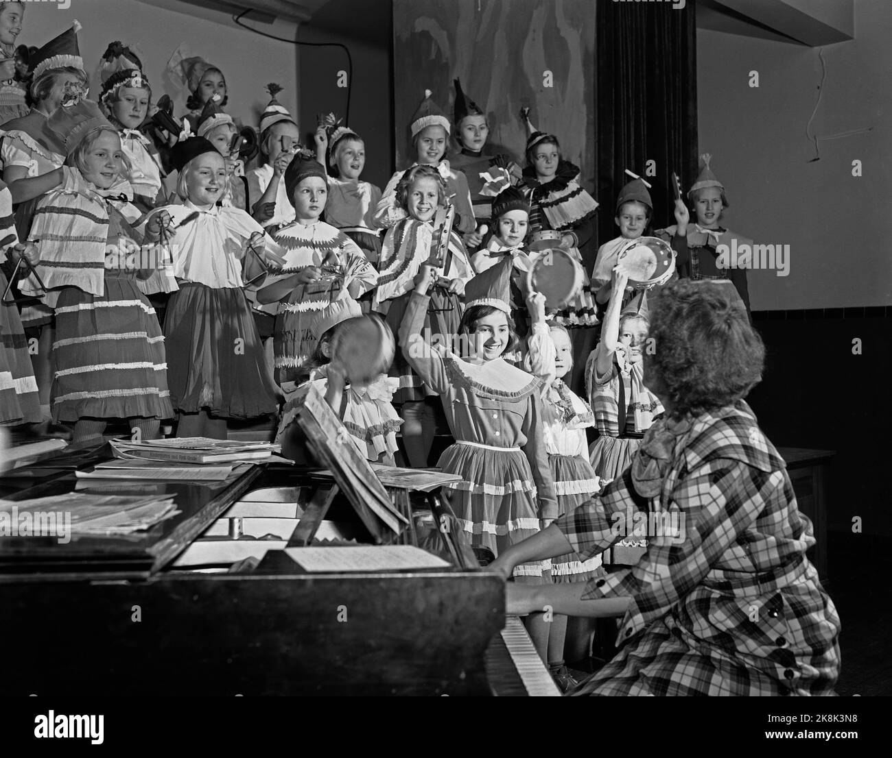 Oslo 31 mai 1952 'Musikk uten tårer' en statistikk fra 1938 over skolefagenes popularitet forteller at sangen er blant de fagene som står lavest. At det ikke behøver å være så, viser et besøk på Majorstua skole i Oslo hvor fru Kirsten Aamodt med sine klasser dimosterer at sang og musikk ikke er to sideordnede begreper, men danner en enhet, og at musikkopplæringen kan være stor og meget givende moro. Lei, classe 4 c slipper segg løs i rytmeorkesteret. Tamburinene i forgrunnen illustrer vårbekkene som bryter gjennom isen. Hver gruppe i orkesteret har sin drakt i mangefarget krepp-papir. Foto Stock