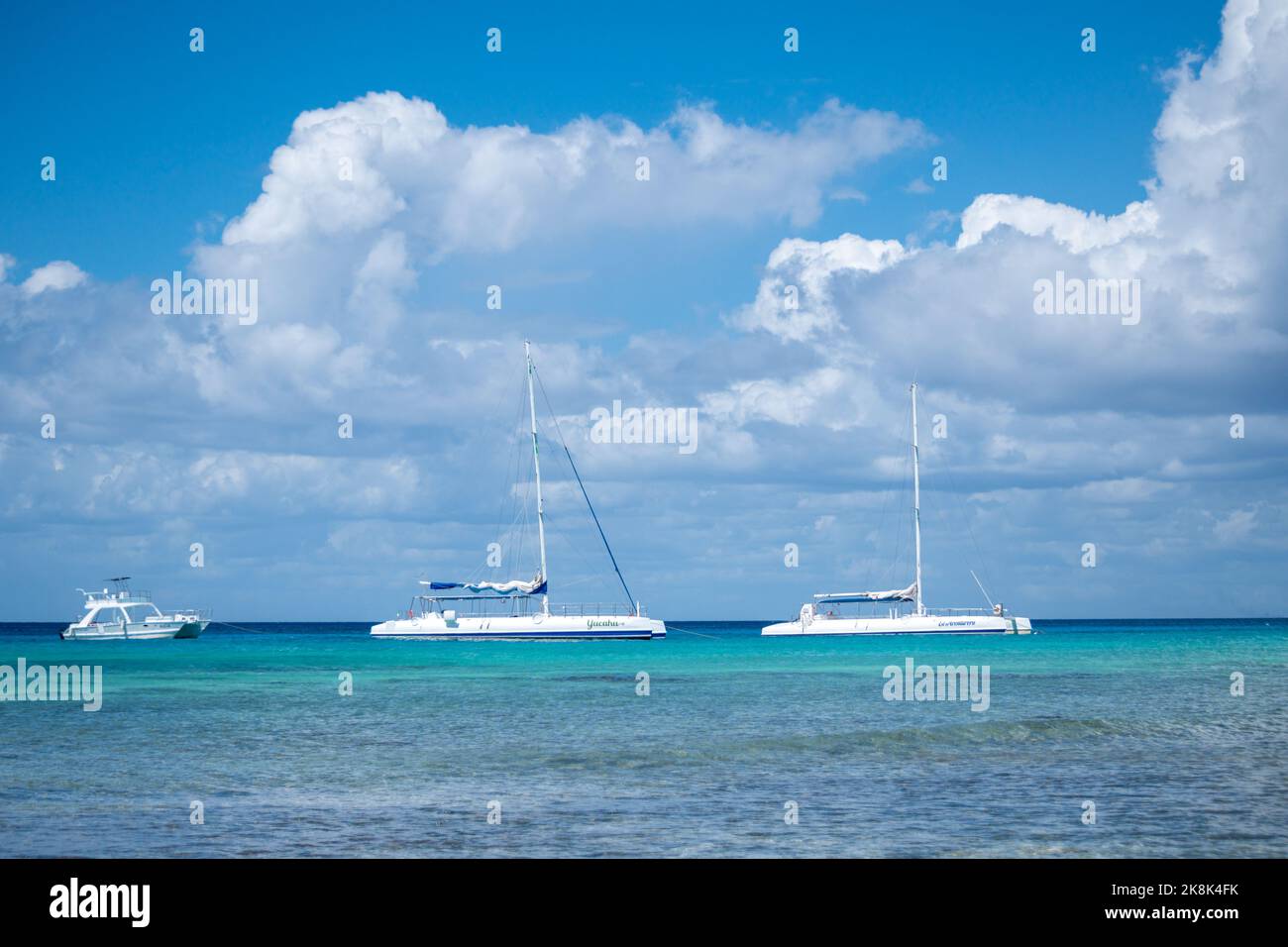 Tre grandi barche bianche nel Mar dei Caraibi con l'orizzonte sullo sfondo sotto un cielo blu sull'isola di Saona Foto Stock