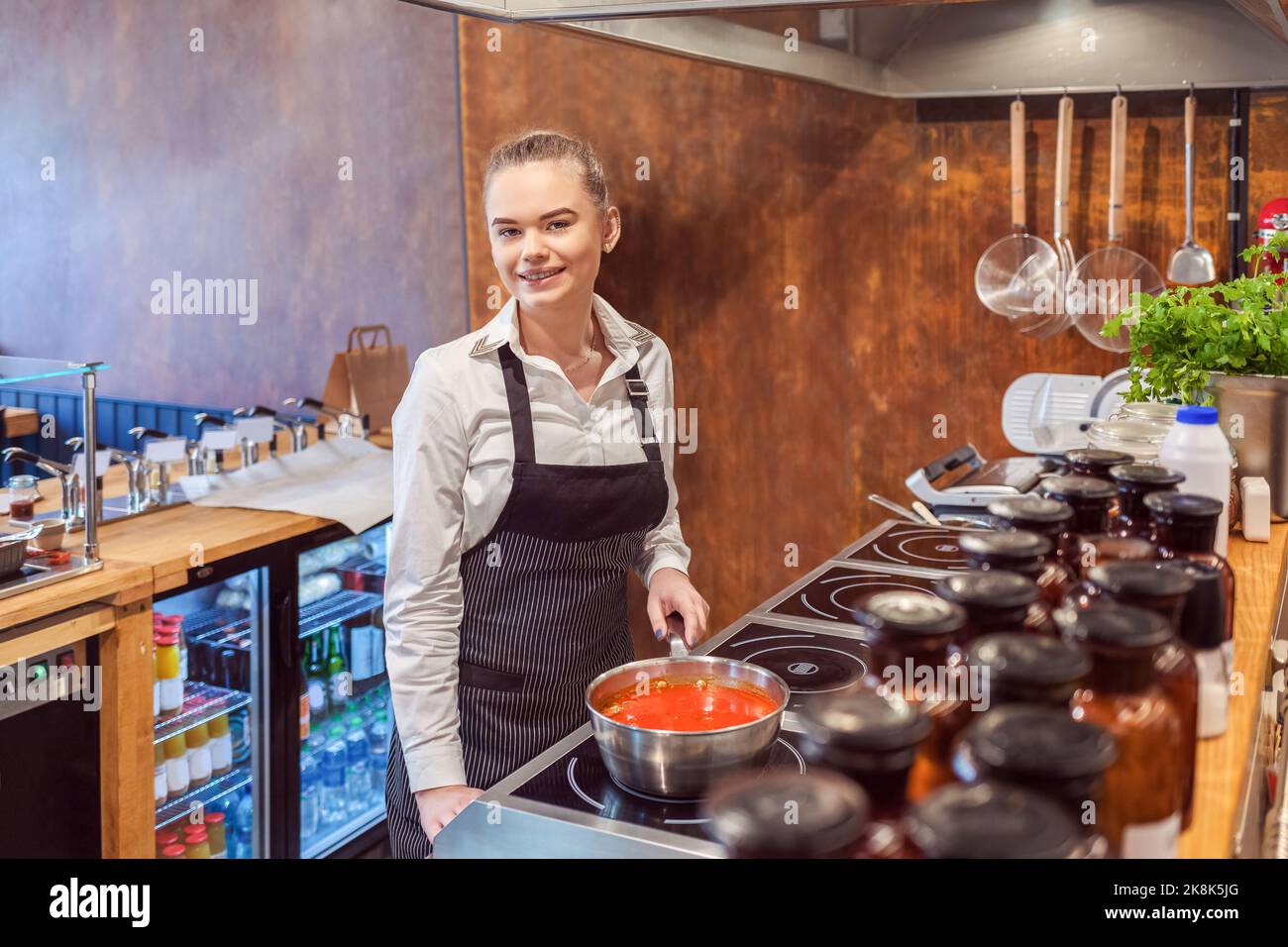 Chef donna preparare salsa di pasta tradizionale sul piano cottura ristorante Foto Stock