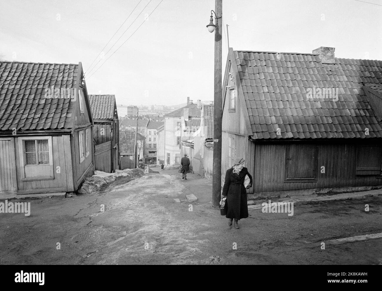 Oslo 19590301 Partito da Enerhaugen. Strada ripida con piccole case caratterizzate da decadimento. Signora anziana in primo piano. Foto: Picture Center / NTB Foto Stock