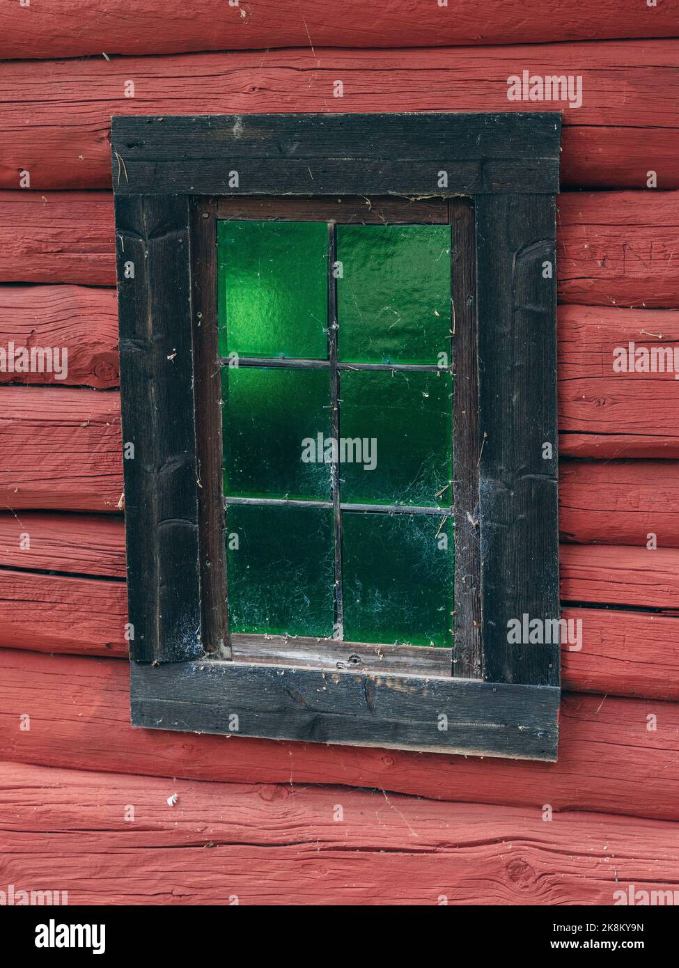 Finestra con vetro verde di una vecchia casa di tronchi al Museo Folcloristico di Valdrembusea, Norvegia, con dipinto rosso, tradizionale locale. Foto Stock