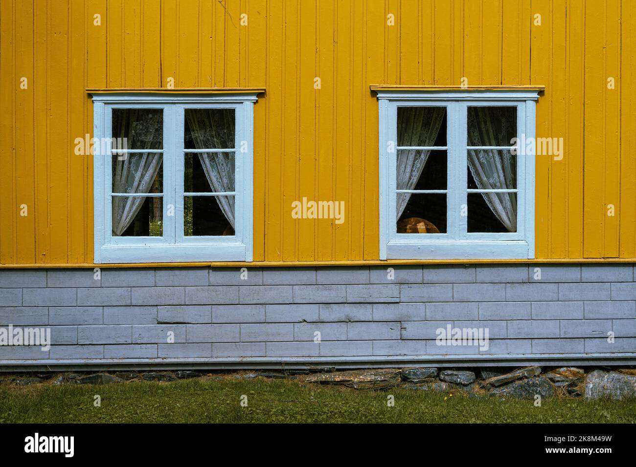 due finestre di una casa di legno giallo Foto Stock