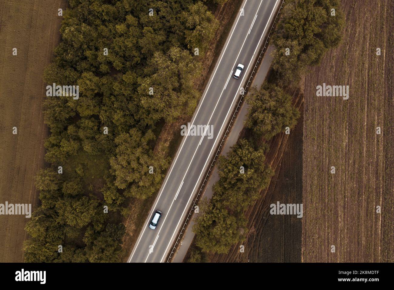 Vista dall'alto dell'autostrada asfaltata diritta attraverso il paesaggio rurale in estate con le automobili che guidano lungo la strada, il drone pov Foto Stock
