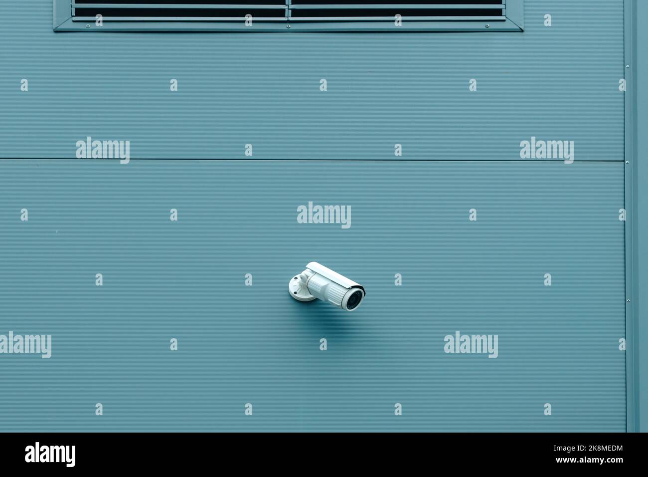 Telecamera di sicurezza per sorveglianza esterna montata sulla parete di un edificio industriale per monitorare l'attività al di fuori dei locali Foto Stock