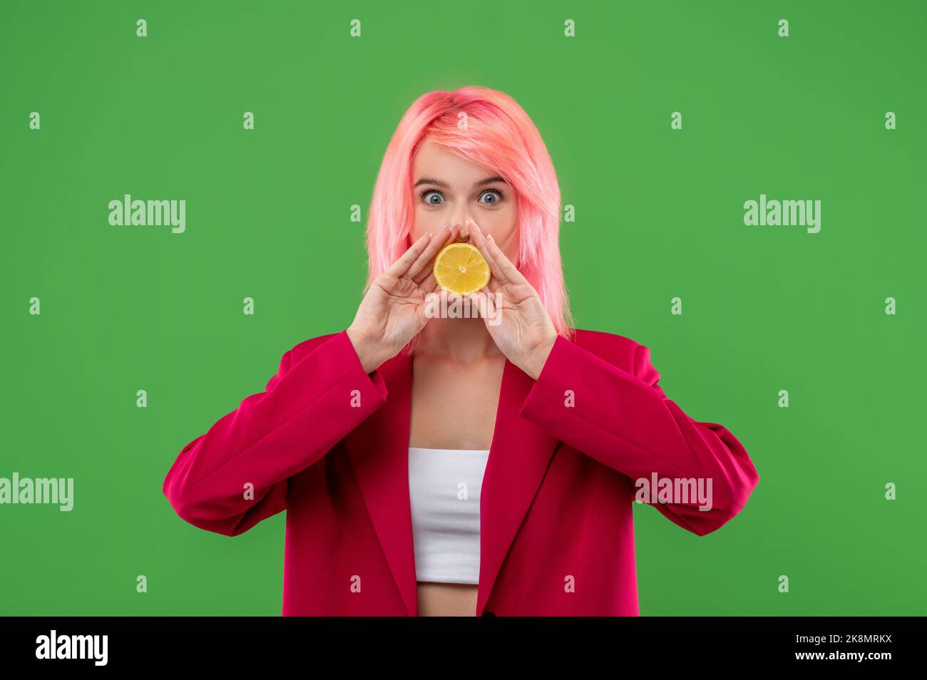 Femmina che ricopre la bocca con agrumi prima della fotocamera Foto Stock