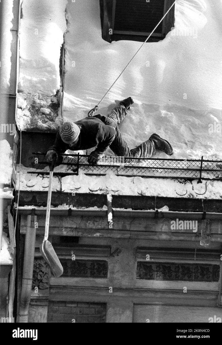 Oslo 19850211: Inverno a Oslo. Sgombrare la neve su un tetto. L'uomo è appeso in corde dal tubo. Foto: Henrik Laurvik, NTB Foto Stock