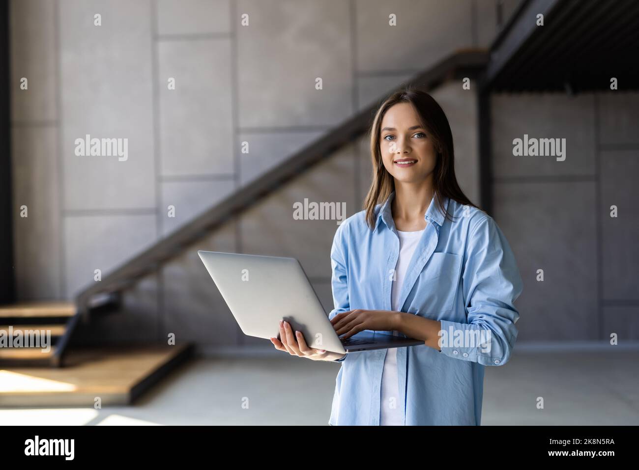 Bella giovane donna sorridente che usa un computer portatile mentre si trova  in un elegante salotto Foto stock - Alamy