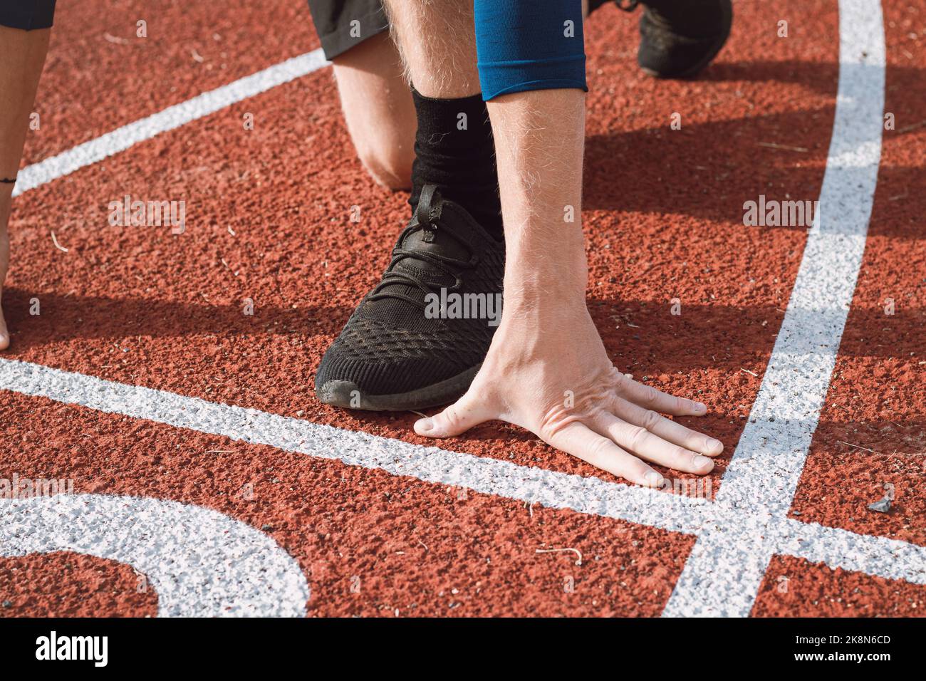 Dettaglio della posizione di un atleta professionista all'inizio di uno sprint 100m. Atletica all'aperto ovale. Foto Stock
