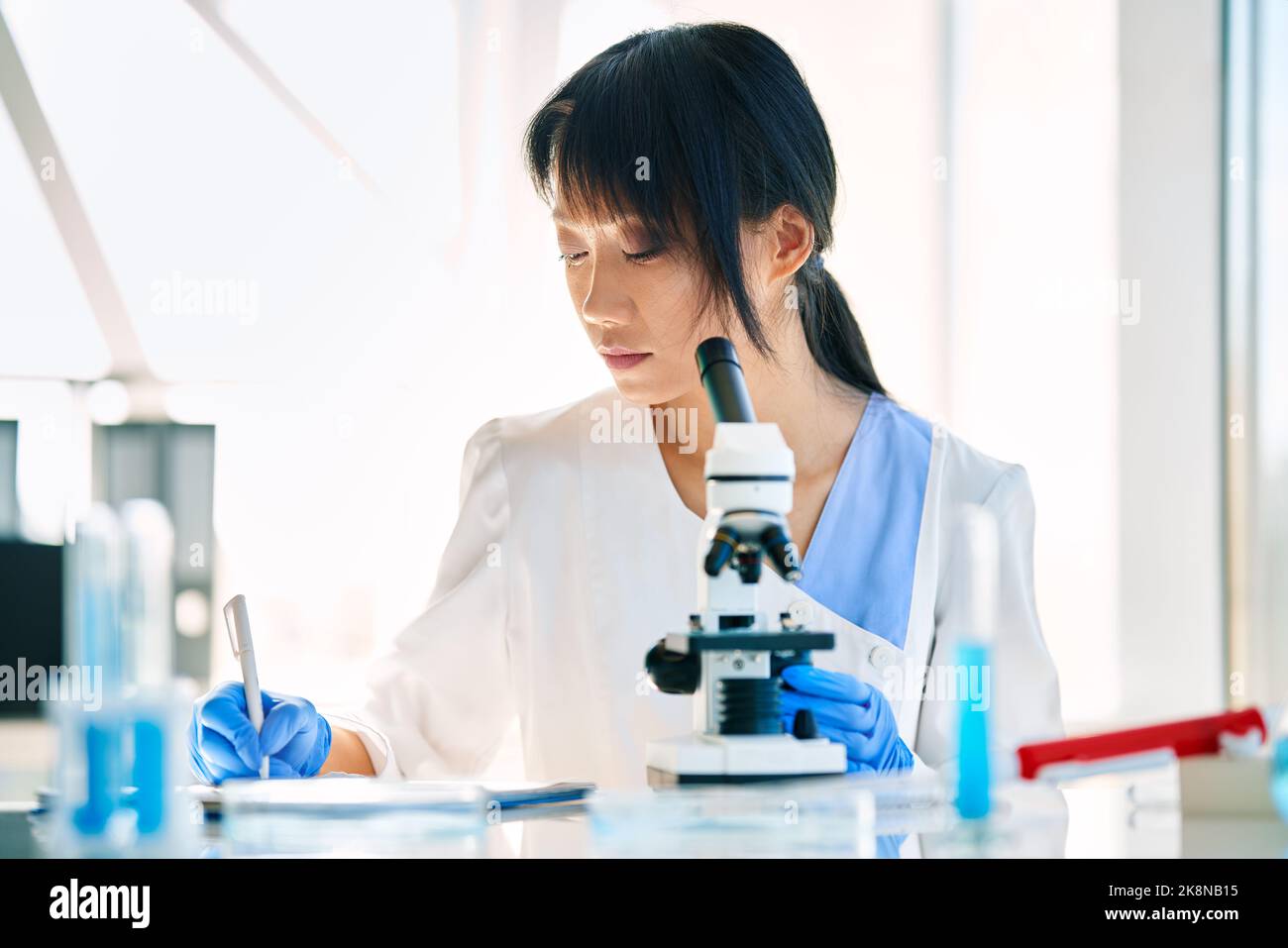 Ricercatore scienziato che lavora scrivendo le informazioni di analisi al moderno laboratorio di ricerca medica. Concetto di medicina, biotecnologia, microbiologia Foto Stock