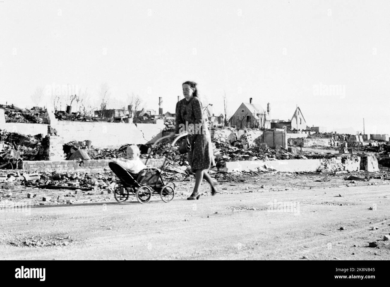 La guerra in Norvegia dopo l'assalto dei tedeschi. Bodø giugno 1940. La distruzione dopo gli attentati dinamitardi perpetrati dai tedeschi negli ultimi giorni del maggio 1940. Donna con bambini in un passeggino passa case che sono livellati con la terra. Foto: NTB Nuova versione ingrandita nuova versione Foto Stock