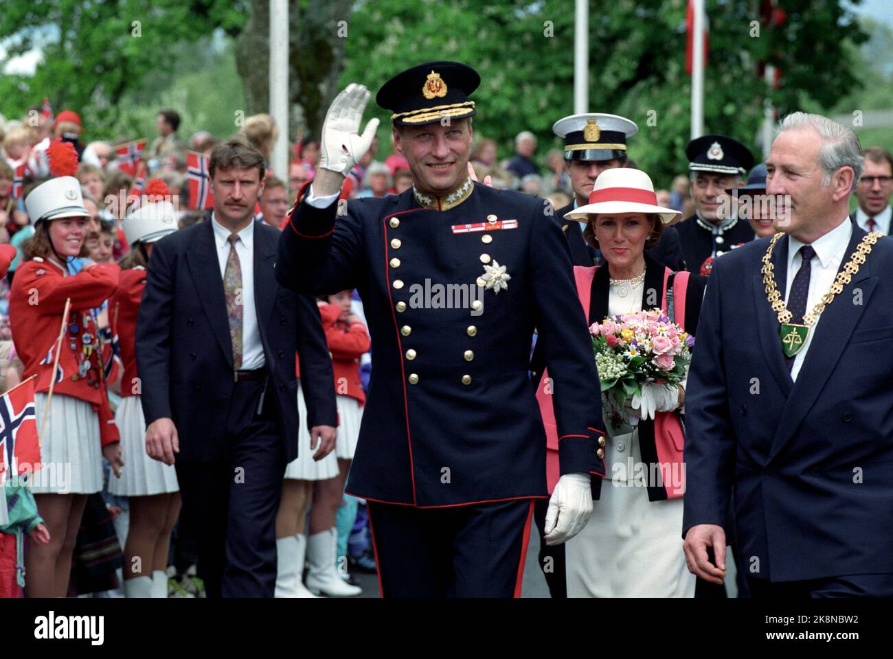 Eidsvoll 19910620: Siggingsferden 1991 giugno. Re Harald V - firma e Sigsninger. Immagine: 1. Il gruppo scout Eidsvoll si è distinto con l'Associazione sportiva Eidsvoll quando il re e la regina e i loro seguaci si sono avvicinati all'edificio Eidsvoll. Qui vediamo anche alcune delle ragazze nel corpo di musica locale sullo sfondo. Re Harald onde. Regina Sonja sullo sfondo. Sindaco Thor Solberg a h. - Guardia di sicurezza fino a v. - Photo: Agnete Brun Foto Stock