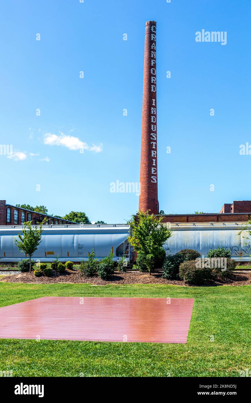 ASHEBORO, North Carolina, USA-26 SETTEMBRE 2022: Fumetto e edificio della storica Cranford Industries, in piedi dietro le auto ferroviarie in centro. Foto Stock