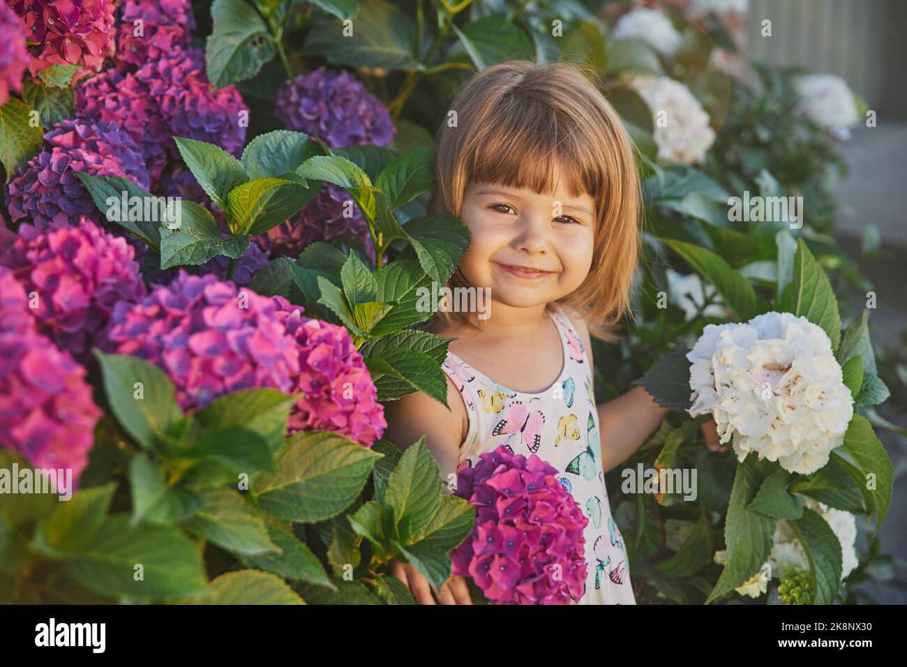 Adorabile bambino vestito come una farfalla vicino ai fiori Foto Stock