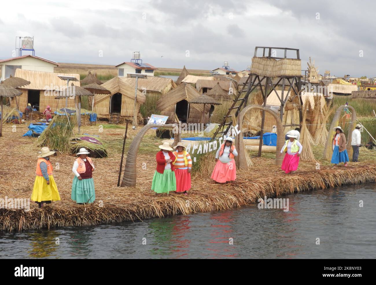 Le donne indigene che si trovano sulla riva del lago presso le isole galleggianti di Uros nel lago Titicaca in Perù Foto Stock