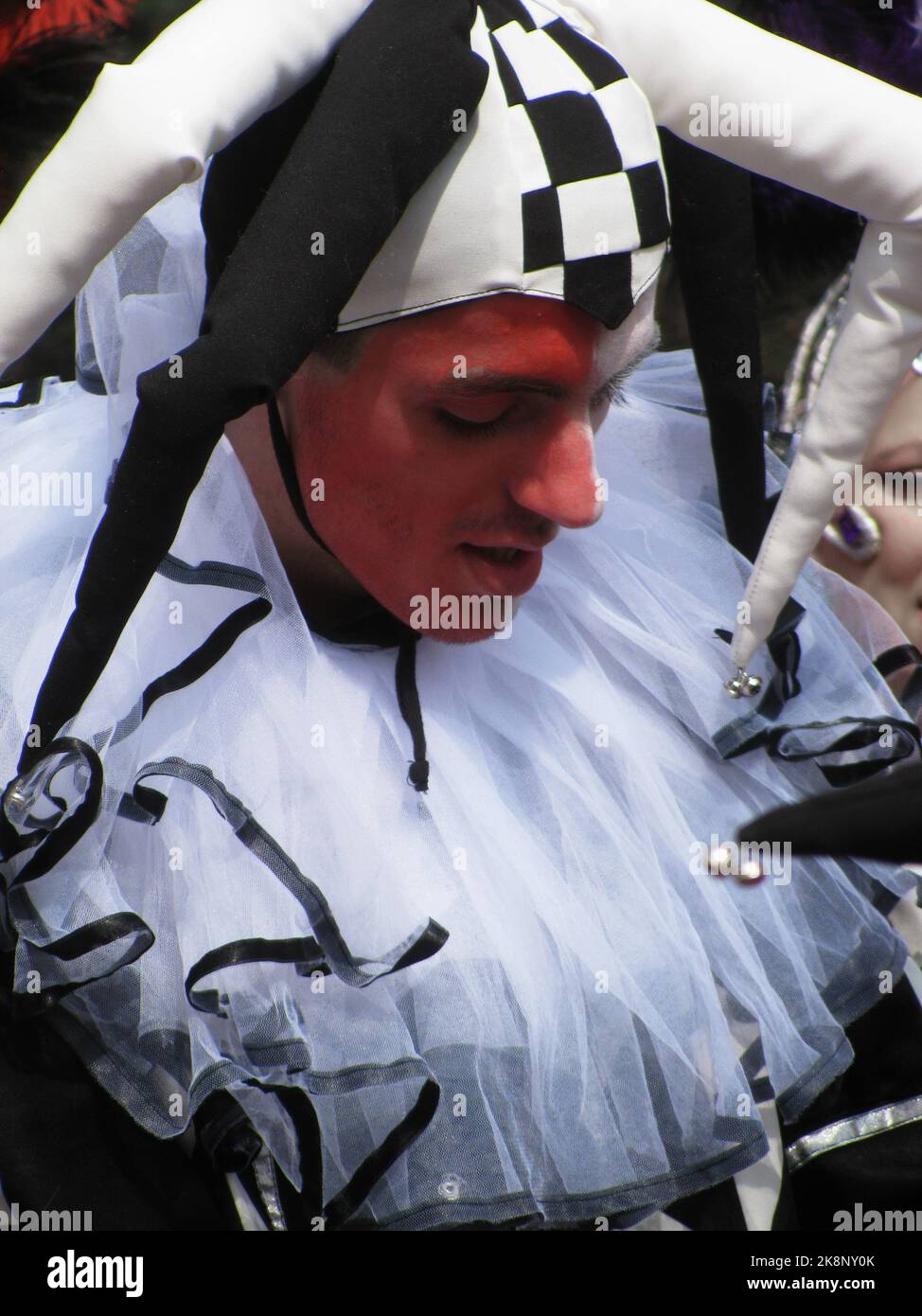 Un giovane con un volto dipinto di rosso in costume di giester bianco e nero durante la parata di Belgrado Foto Stock