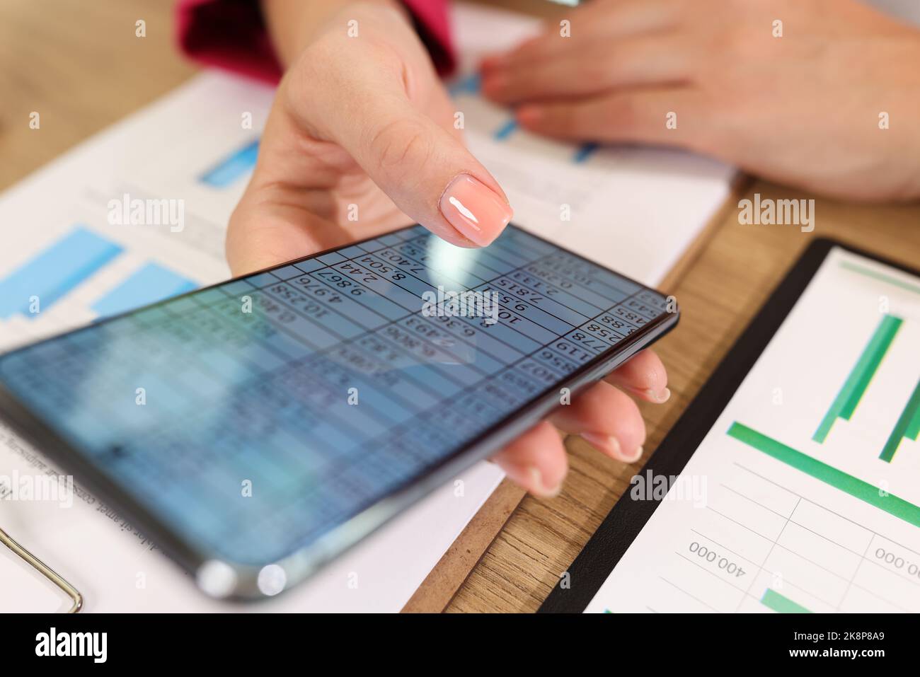 Le mani femminili tengono in mano uno smartphone moderno con dati statistici sullo schermo Foto Stock