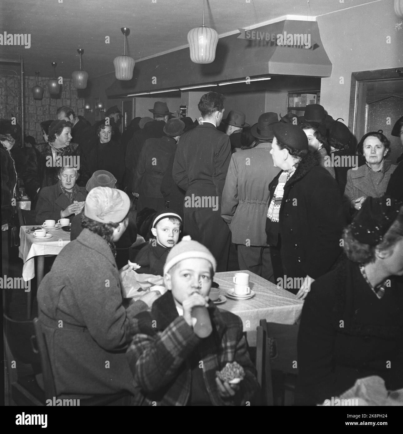 Arvika, Svezia 195412. Le casalinghe norvegesi hanno conquistato Arvika. Nel mese di dicembre, la città è stata invasa fino a 20 autobus norvegesi imballati da casalinghe shopping di Natale. Lunghe code di casalinghe nel negozio coloniale e il negozio di giocattoli per acquistare a buon mercato ciò di cui hanno bisogno per Natale. Alcuni giorni ci sono fino a 6-700 donne di shopping di Natale. Ci sono anche delle code per fare uno spuntino come qui nella foto. Foto: Aage Storløkken / corrente / NTB Foto Stock