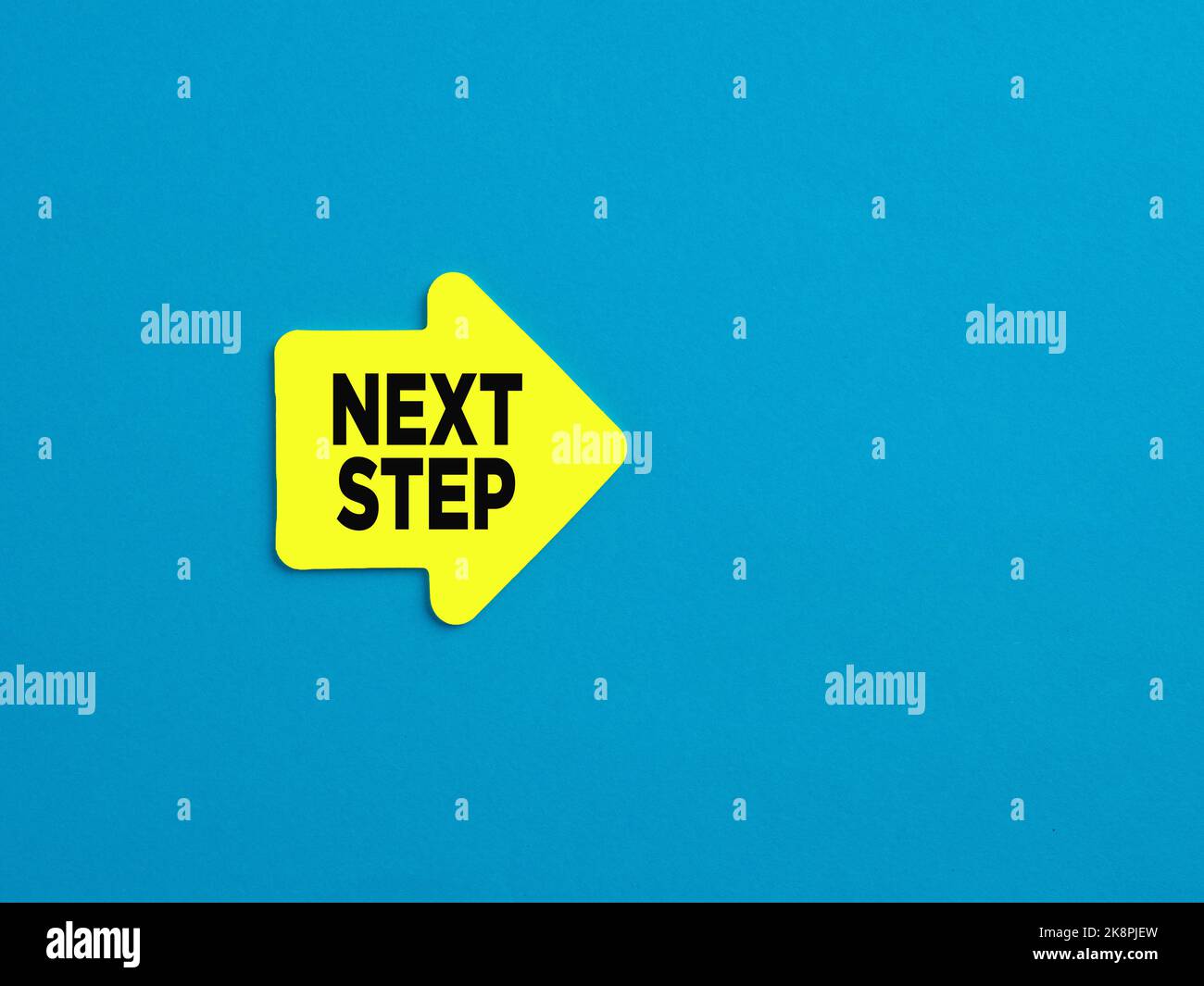 Il passo successivo nel business, nella carriera o nel concetto di istruzione. Adesivo giallo a forma di freccia con il messaggio punto successivo su sfondo blu. Foto Stock