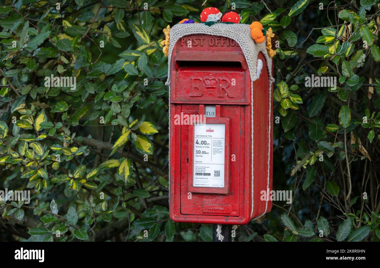 Tradizionale casella postale Royal Mail rossa britannica con decorazioni in cima, tradizioni locali Foto Stock