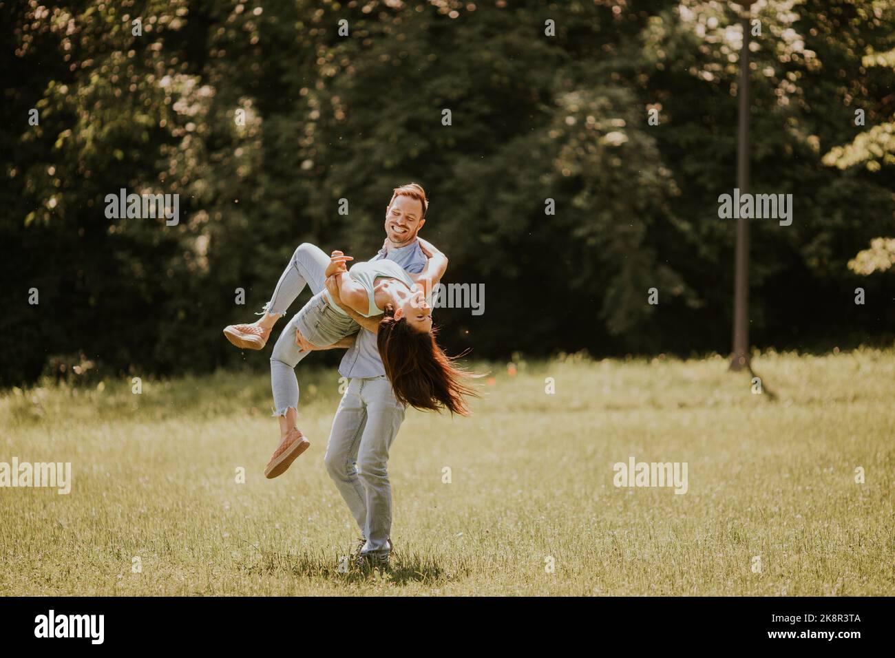 Felice giovane coppia innamorata al campo di erba su una giornata estiva Foto Stock
