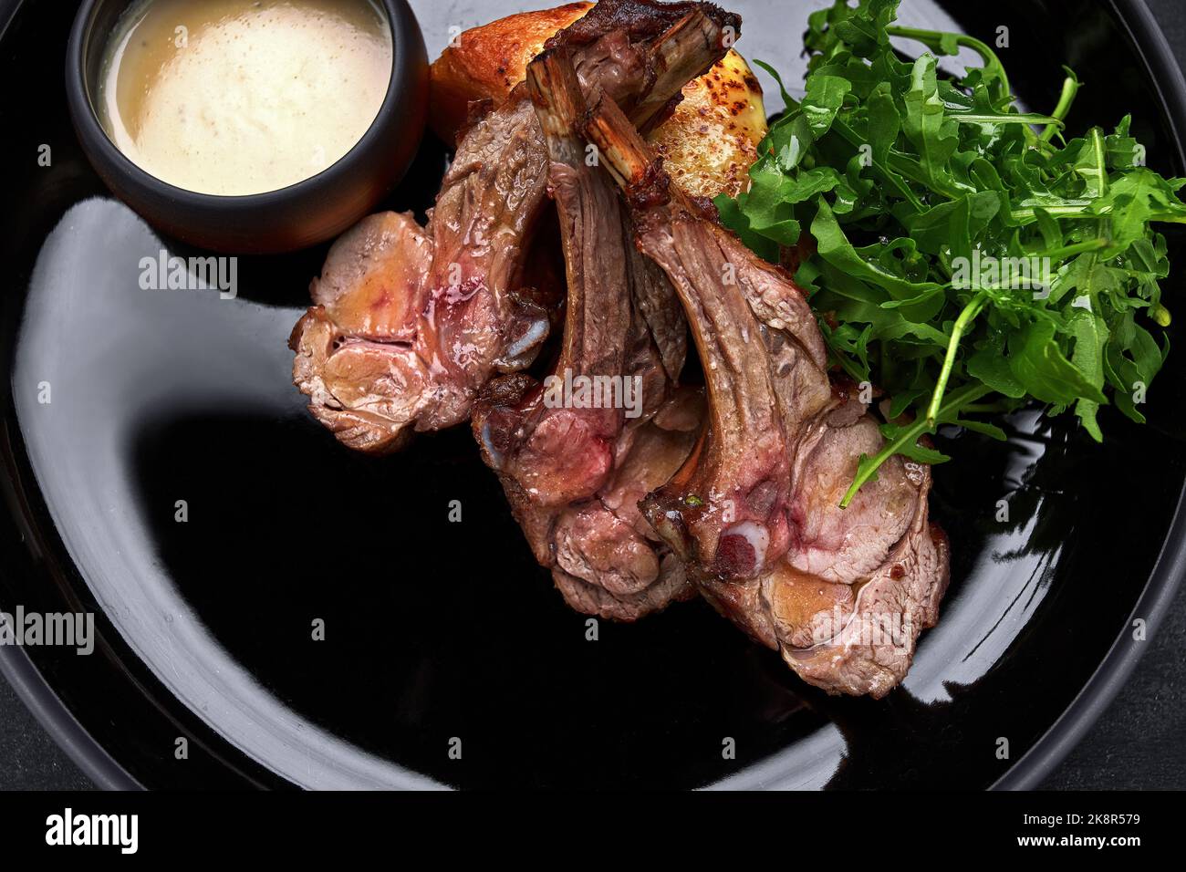 Costolette di agnello alla griglia su un piatto, con salsa ed erbe aromatiche Foto Stock