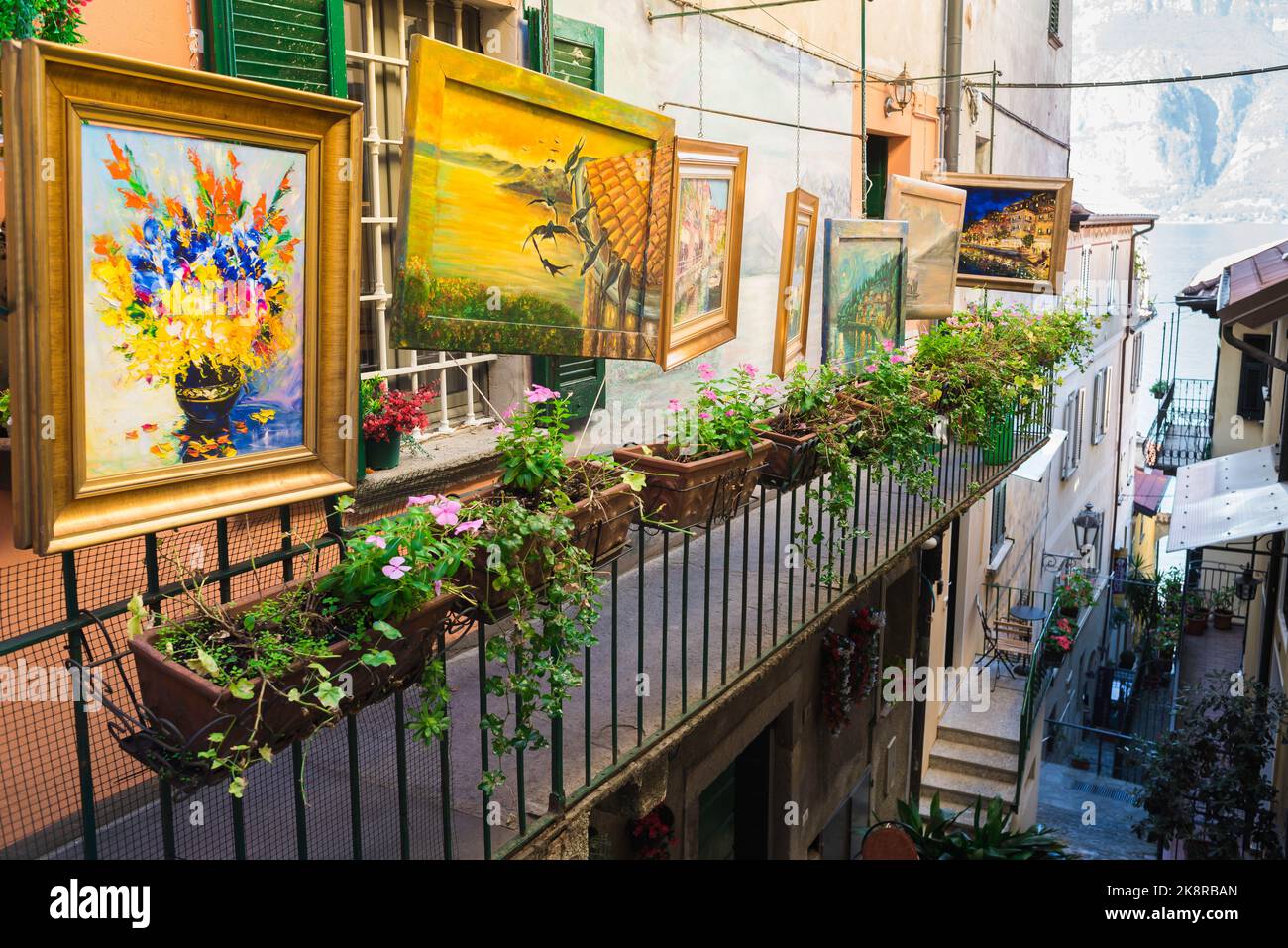 Colori della strada Italia, vista dei dipinti in vendita esposti su un balcone nel suggestivo centro storico di Varenna sul lago di Como, Lombardia, Italia Foto Stock