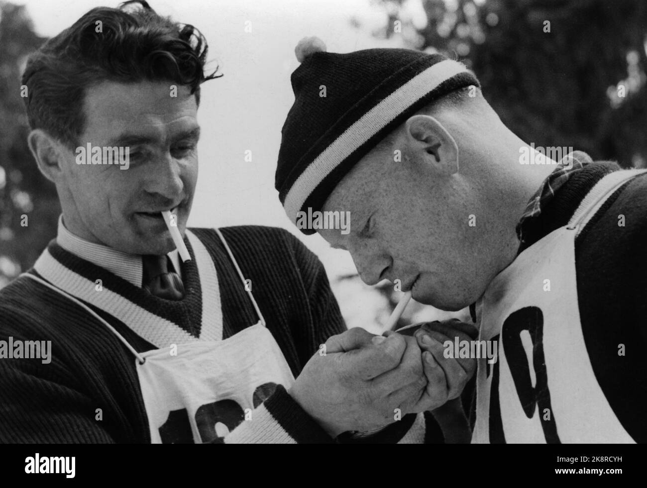 Il corridore combinato Simon Slåttvik durante la gara di salto a Holmenkollen. Accende una sigaretta per Erling KROKEN, e prende una sigaretta da solo. All'epoca il fumo non era raro. Foto: Knut Holm / NTB Foto Stock