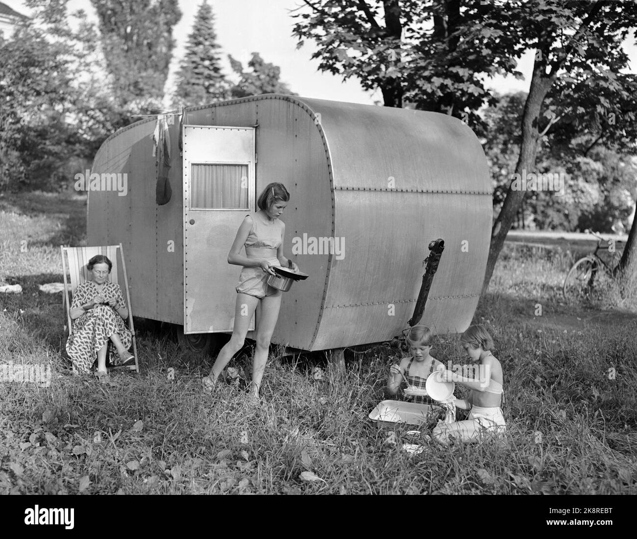 HUK 19530612 Campeggio a Huk. Ecco una famiglia felice di cinque membri, madre, padre e tre ragazze, che sono in vacanza in una carovana. La cena è fatta, e le ragazze prendono i piatti all'aperto, mentre la madre si inginocchiava nella sedia di fuga. Foto: Jan Stage / NTB / NTB HUK Norvegia 19530612. Campeggio a HUK. Una famiglia felice di cinque persone; Madre, Padre e tre Figlie in Caravan. La cena è finita e le ragazze fanno i piatti all'aperto mentre la madre è cracking in qui sedia a sdraio. Foto: Jan Stage/ NTB/ NTB Foto Stock