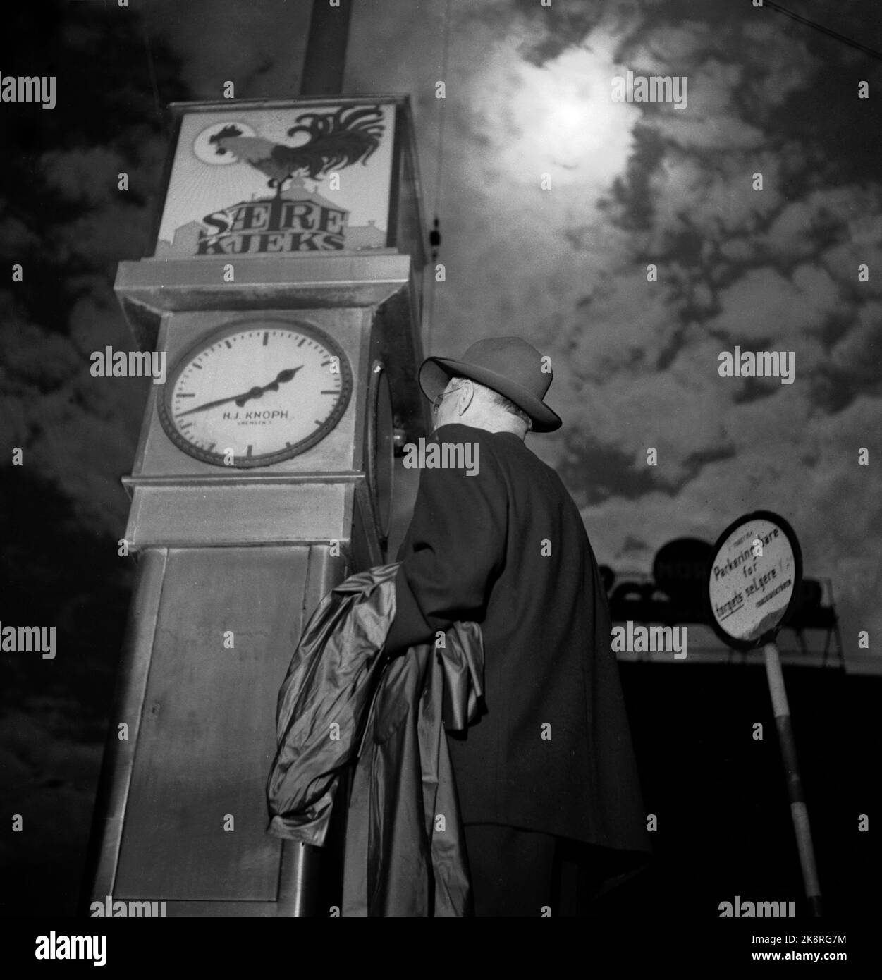 Oslo 19540630 eclissi solare totale in Norvegia. L'eclissi era totale in una fascia che si estendeva a sud-est sopra la parte più meridionale del paese. Tale era la situazione alle dieci e alle due metà del pomeriggio. L'uomo guarda l'orologio, l'eclisse solare sullo sfondo. Pubblicità per biscotti Sætre con gallo nel logo sull'orologio. Foto: NTB / NTB Foto Stock