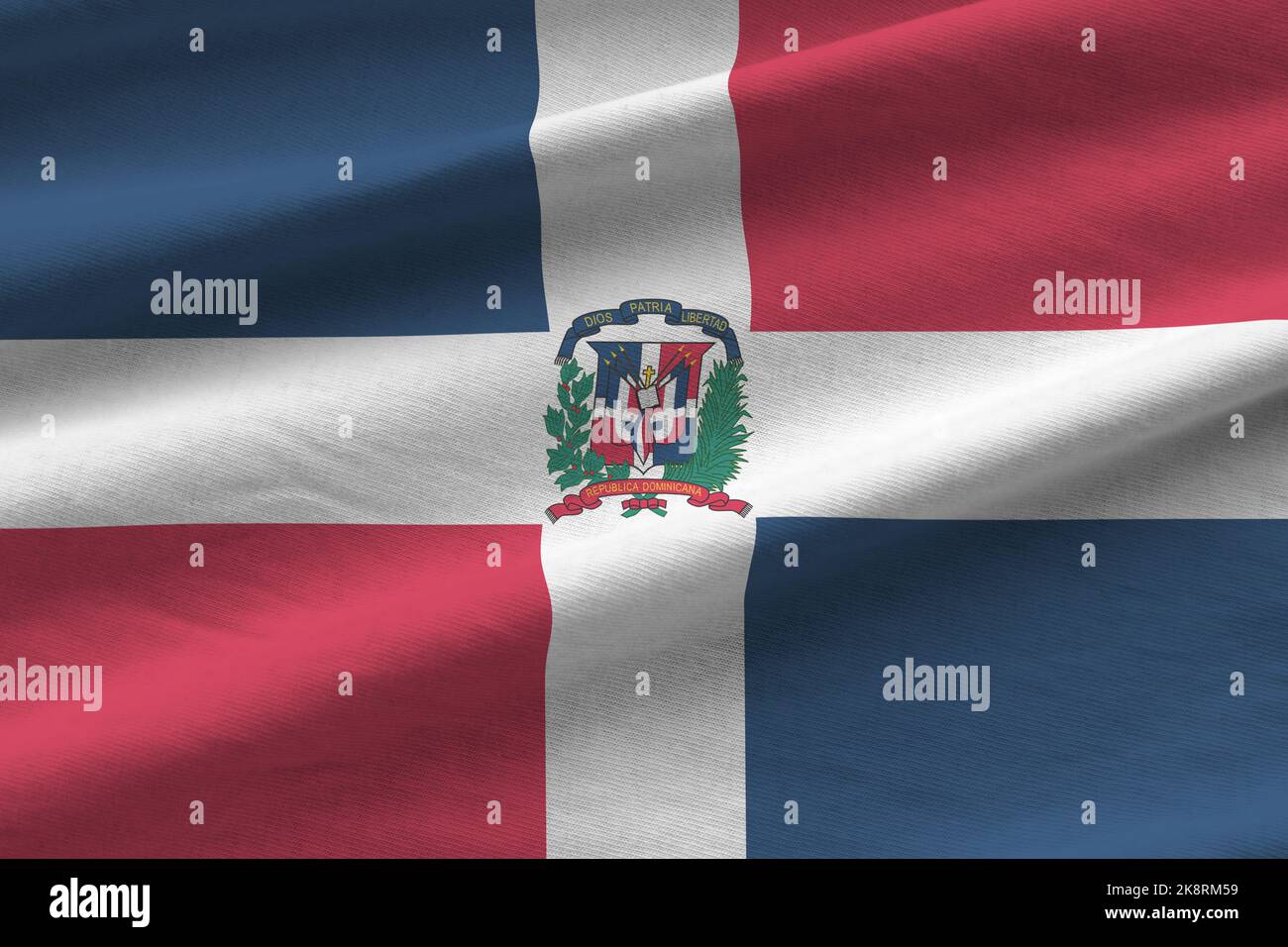 Bandiera della Repubblica Dominicana con grandi pieghe che sventolano da vicino sotto la luce dello studio all'interno. I simboli e i colori ufficiali in tessuto banner Foto Stock