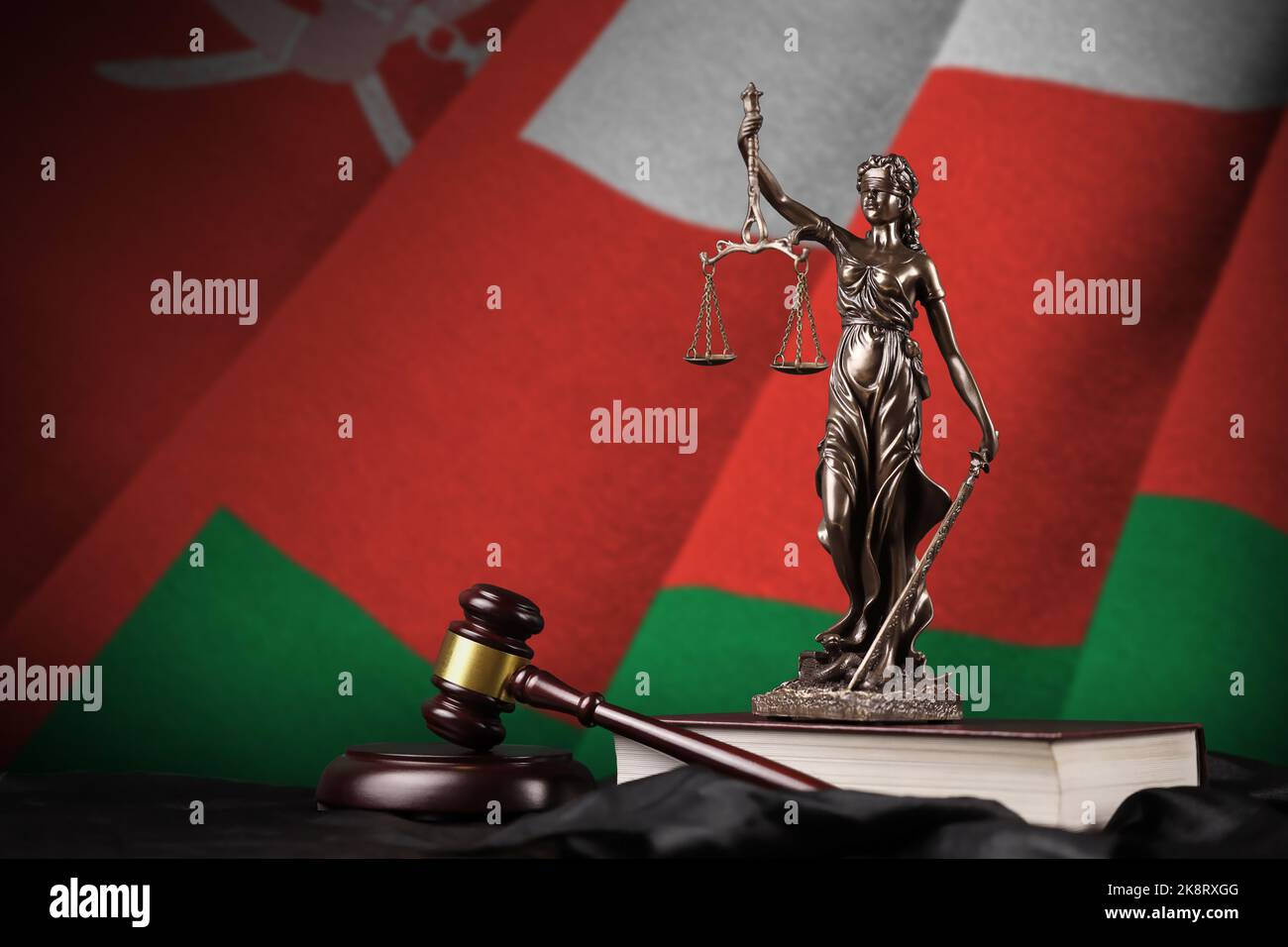 Bandiera dell'Oman con statua di giustizia, costituzione e martello giudice su tendaggi neri. Concetto di giudizio e di punizione Foto Stock
