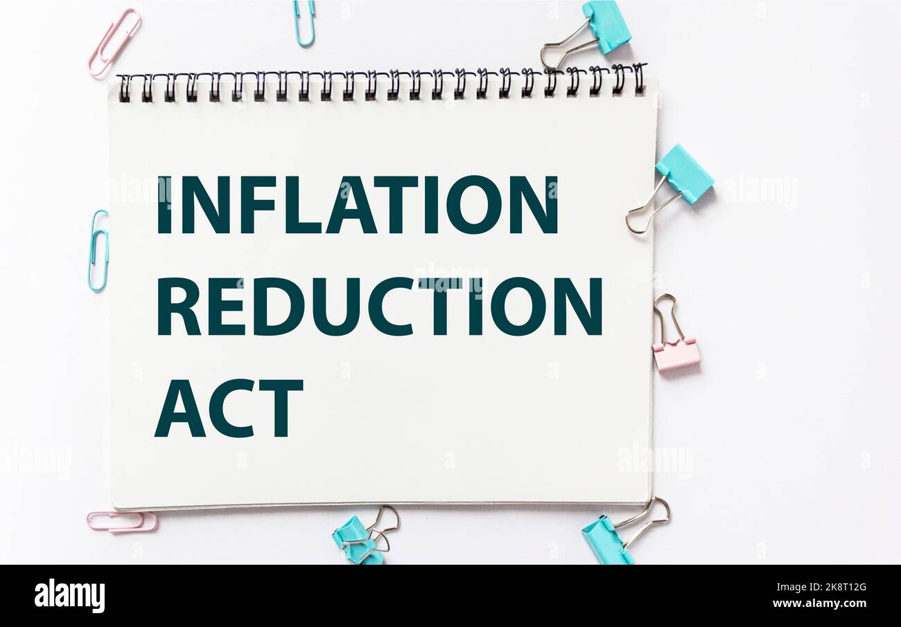 Il testo della legge di riduzione di inflazione su un taccuino, accanto ad esso sono graffette di carta multicolore su uno sfondo bianco Foto Stock