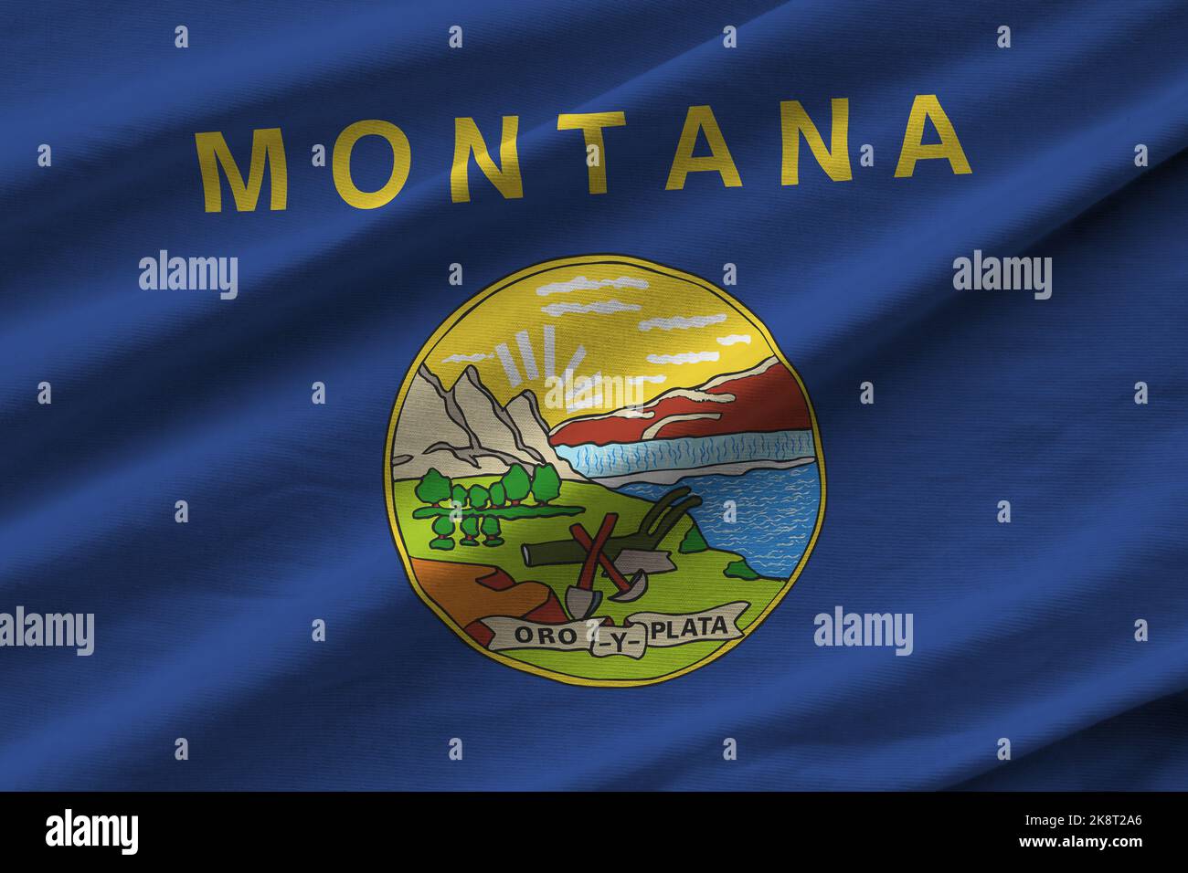 Bandiera dello stato degli Stati Uniti del Montana con grandi pieghe che sventolano da vicino sotto la luce dello studio al chiuso. I simboli e i colori ufficiali in tessuto banner Foto Stock