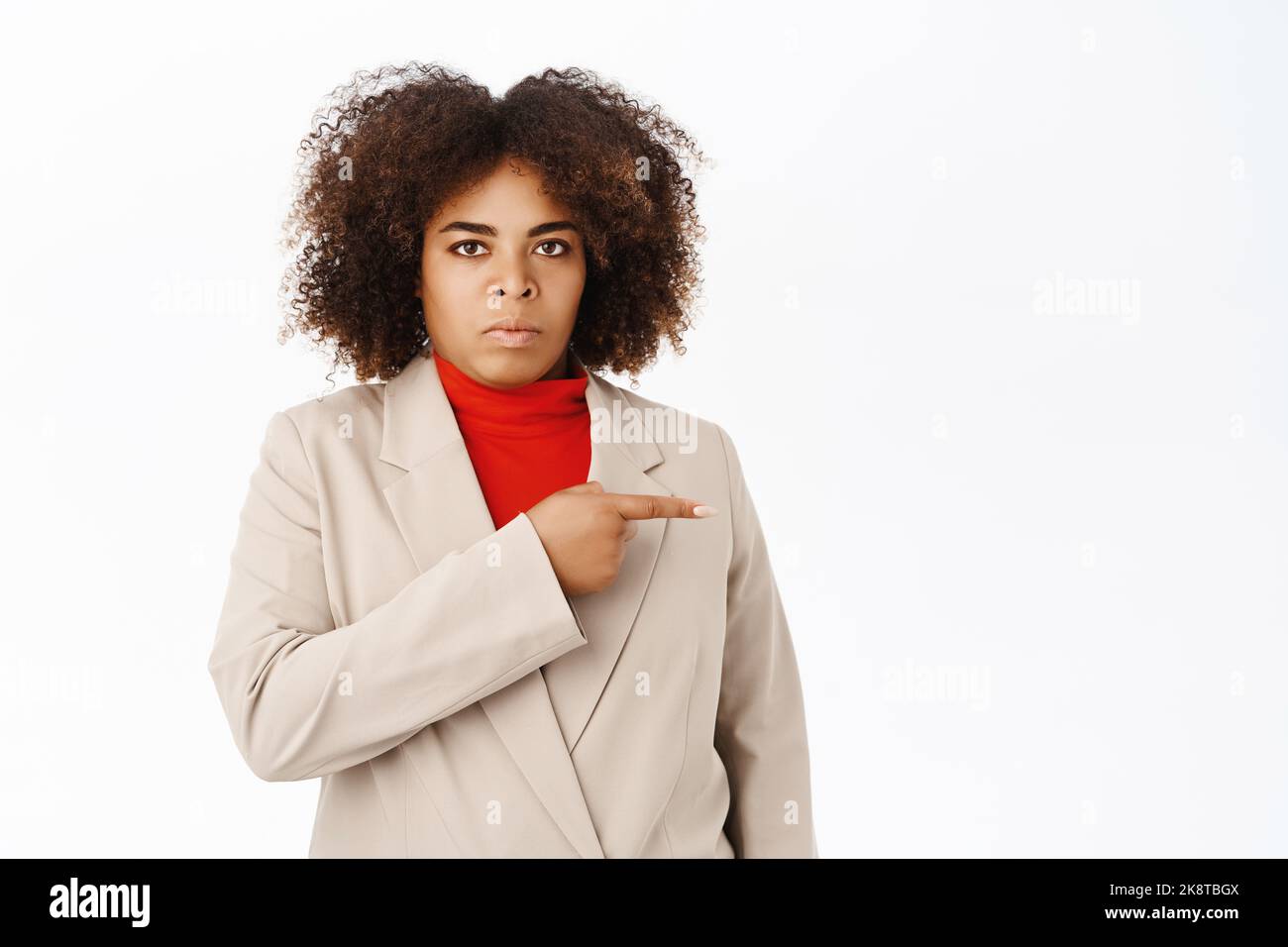 Seccato afroamericano venditore, ufficio di lavoro punta a destra a banner o copia spazio per il logo, sembra fastidioso e sconvolto, si alza su bianco Foto Stock