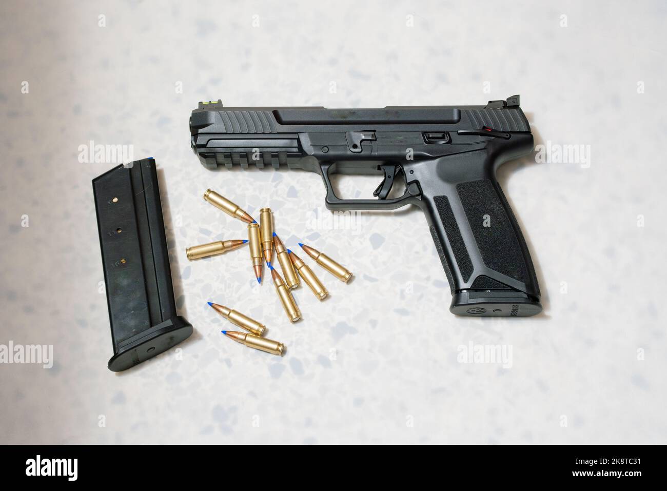 Immagine di un'arma da fuoco accanto a proiettili su sfondo bianco. Foto Stock