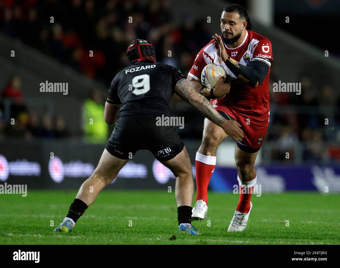 Il ben Murdoch-Masila di Tonga (centro) è affrontato dal Wales Matthew Fozard (a sinistra) durante la partita di Coppa del mondo di Rugby League D al Totally Wicked Stadium, St Helens. Data immagine: Lunedì 24 ottobre 2022. Foto Stock