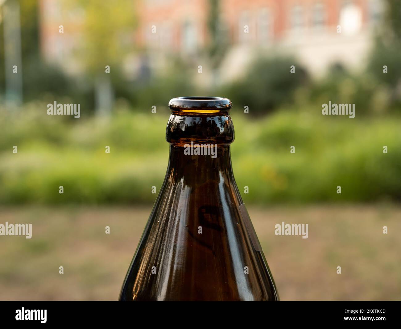 Primo piano del collo della bottiglia di una bottiglia di birra tedesca. La forma rastremata del materiale in vetro marrone è comune. Il tappo a corona è stato rimosso dalla bevanda. Foto Stock