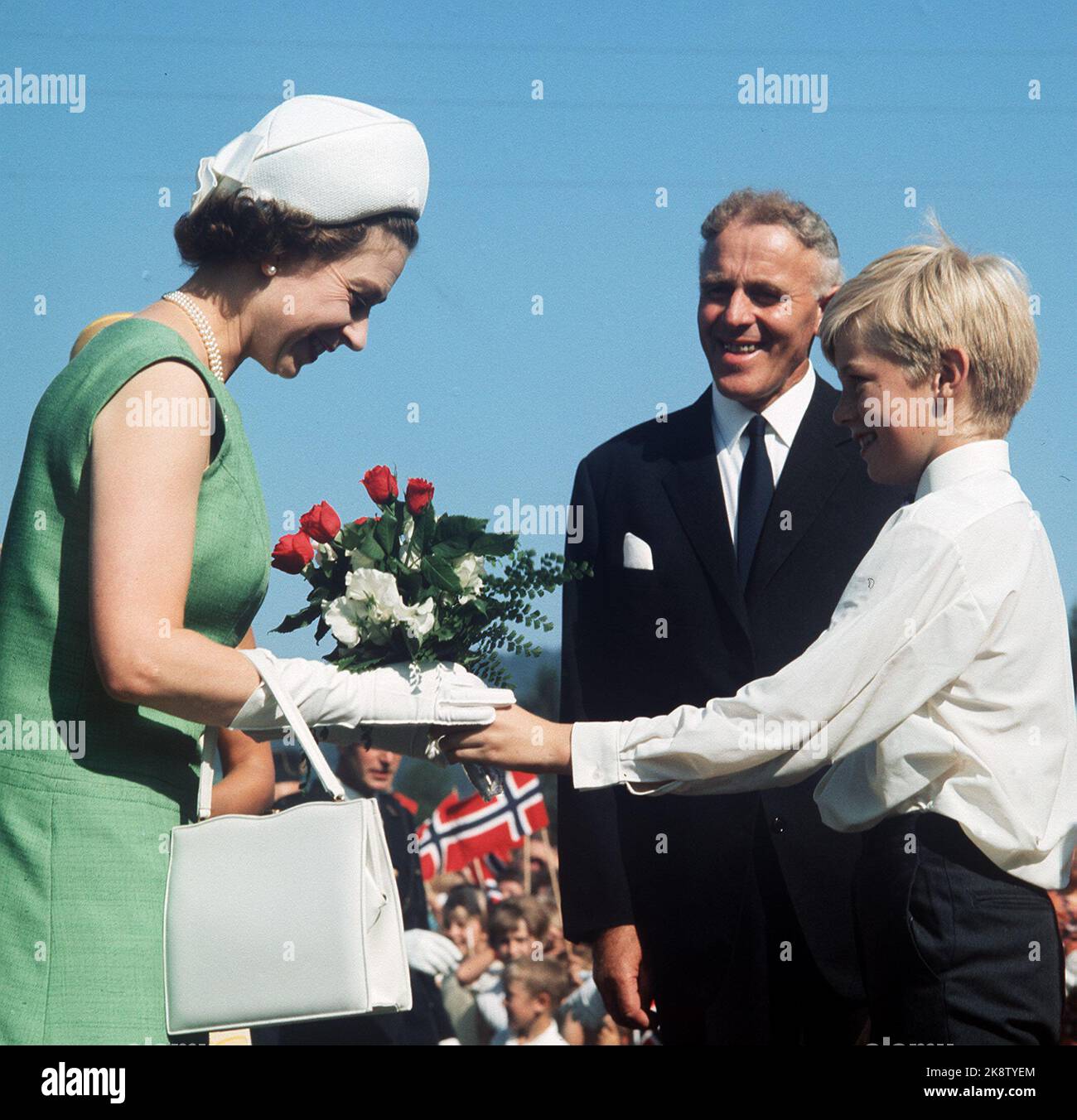 Flå 19690811. Regina Elisabetta in Norvegia con la famiglia. Qui, la Regina è accolta dal primo Ministro per Borten, che ha invitato la Casa della Regina per il pranzo. Un ragazzo consegnò alla Regina un bel bouquet di fiori. Sorridente. Abito verde, borsa bianca, guanti e cappello. Dias See BM Queen Elizabeth. Foto Stock