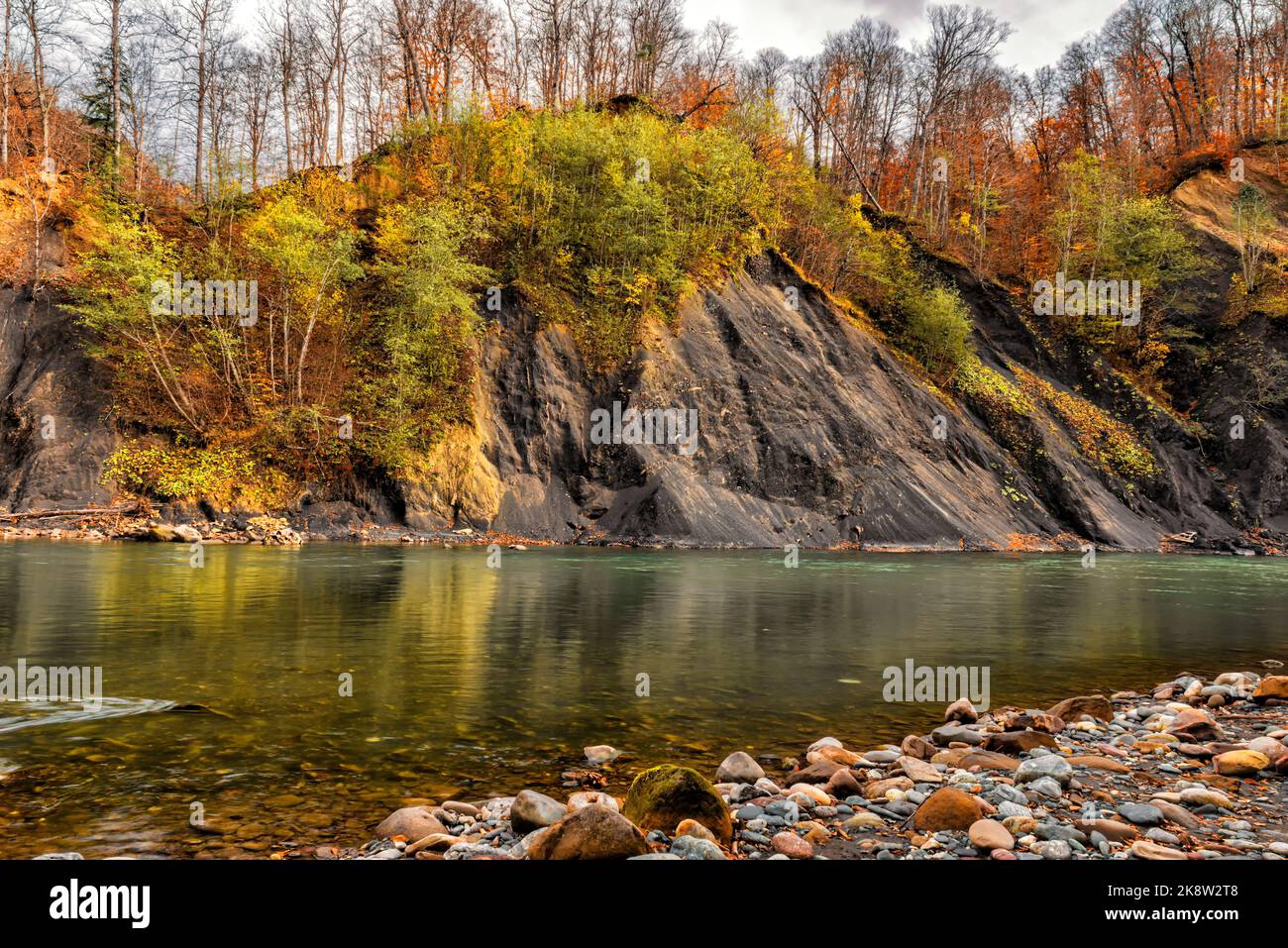 Bellissimo paesaggio autunnale del fiume che scorre ai piedi delle montagne con ripide rive Foto Stock