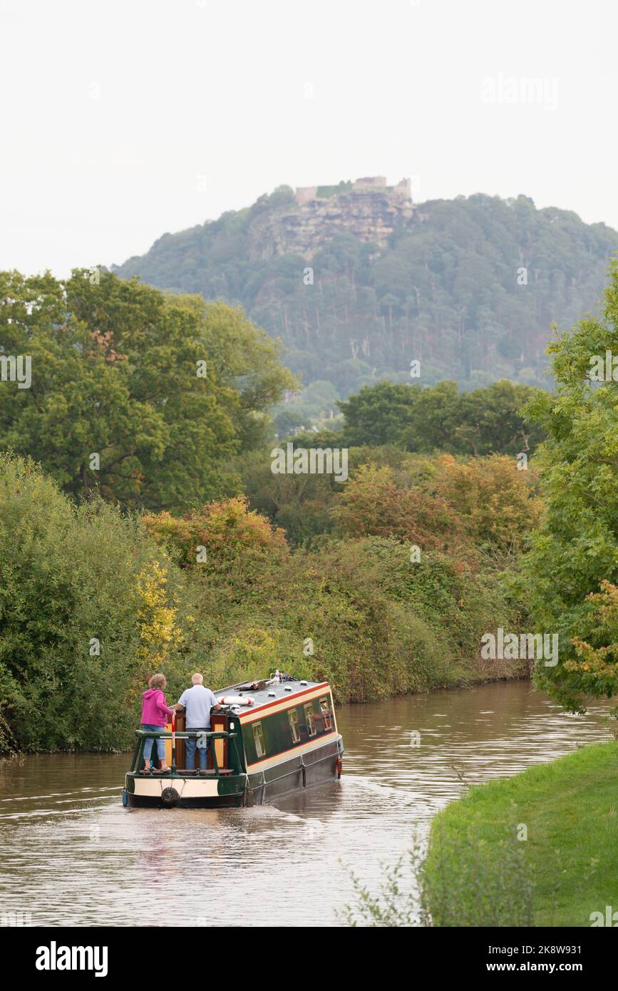 Narrowboaters navigando nel canale Shropshire Union in autunno in vista delle Crags Rocky del Castello di Beeston a Cheshire Foto Stock