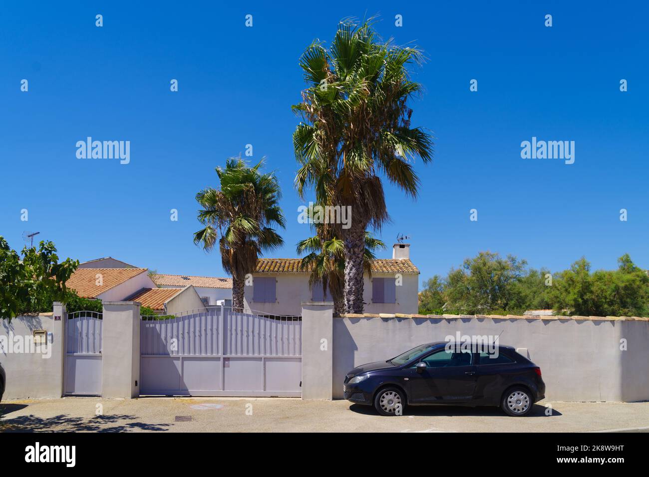 tipica casa mediterranea dietro le mura con una macchina parcheggiata di fronte Foto Stock