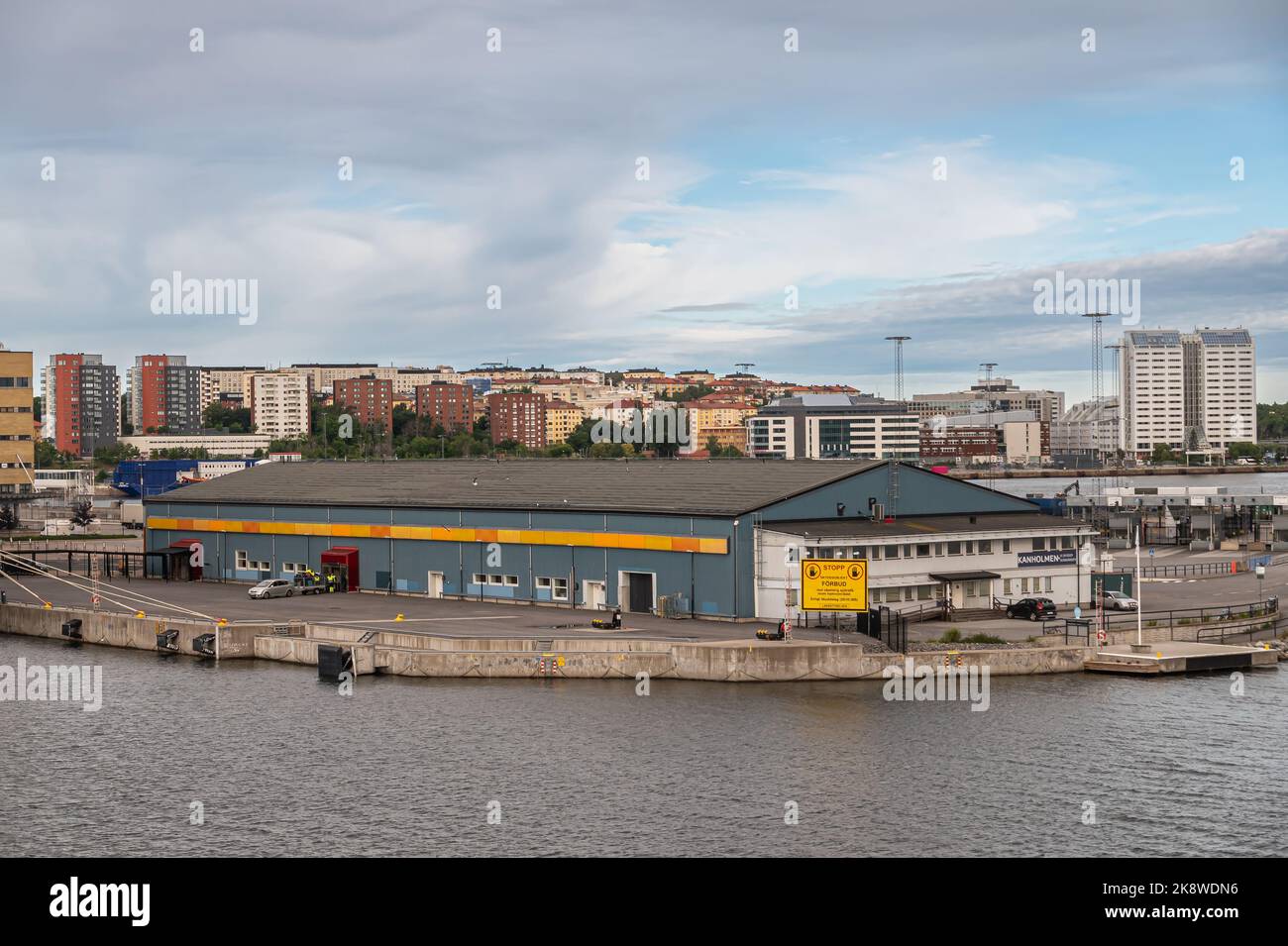 Svezia, Stoccolma - 16 luglio 2022: Kanholmen blu-bianco costruzione di gestione di progetti di costruzione costruzione costruzione costruzione alla fine del molo nel porto di Frihamnen sotto il paesaggio blu Foto Stock