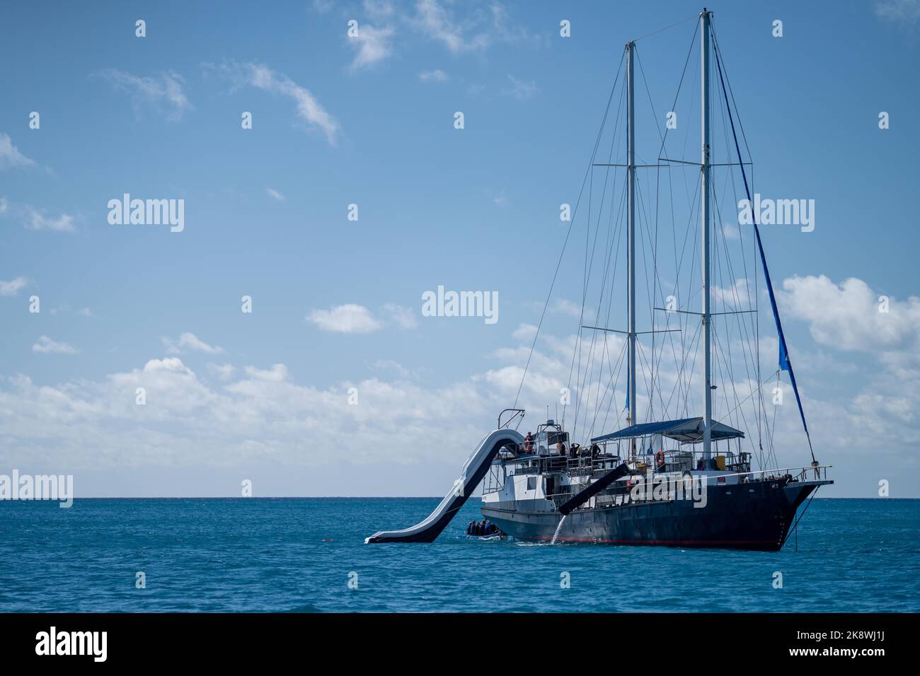 Isola tropicale nella Grande barriera Corallina, con yacht a vela. Barche e super yacht in vacanza. Viaggi in viaggio sull'oceano Foto Stock