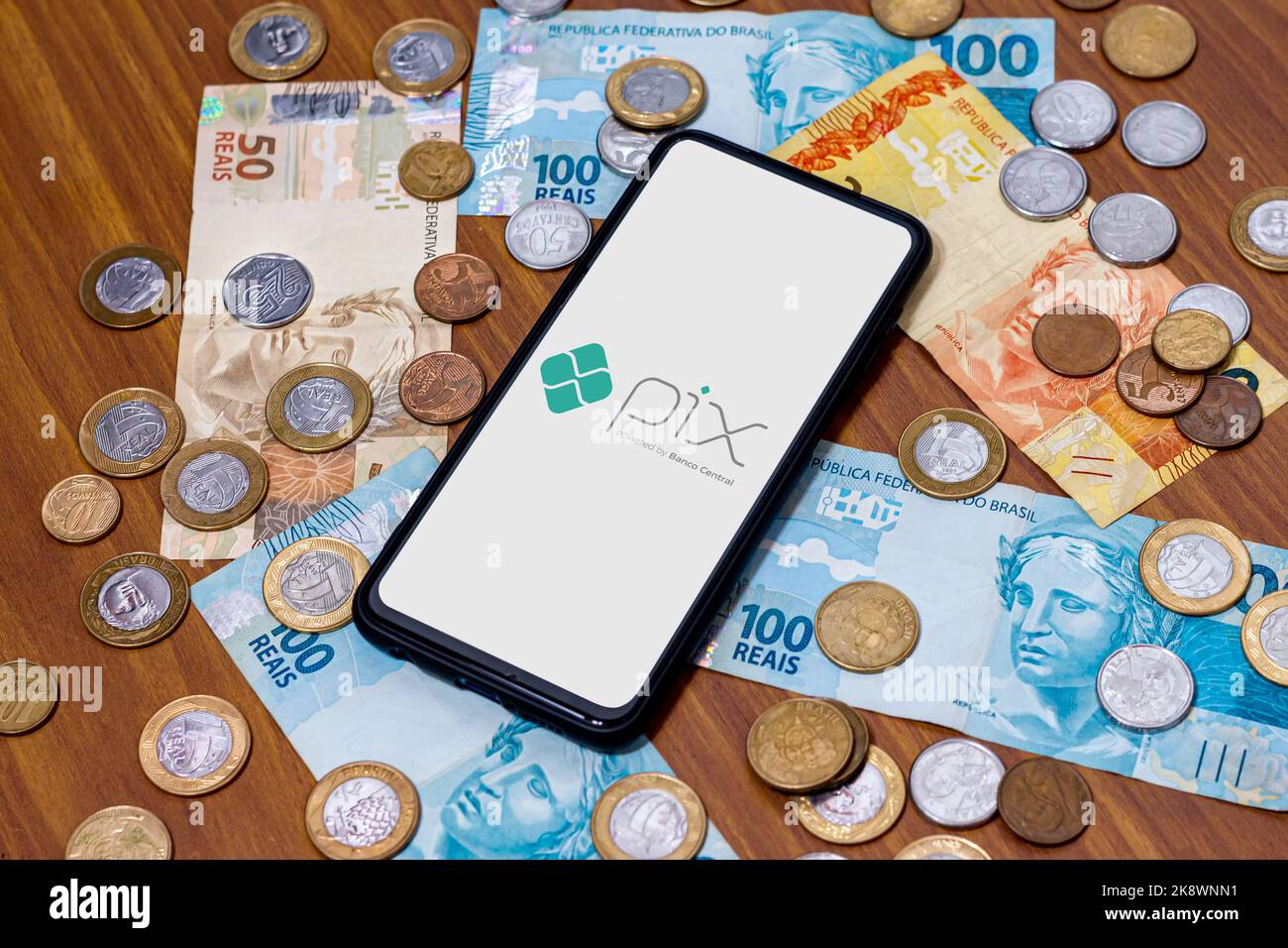 San Paolo, Brasile. 8 MARZO 2022: Logo PIX sullo schermo dello smartphone con più monete intorno. PIX è il nuovo sistema di pagamento e trasferimento della Brazilia Foto Stock